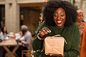 Curious young woman opening Christmas gift