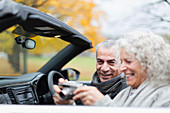 Senior couple using digital camera in convertible
