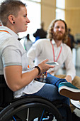 Woman in wheelchair with smart phone at conference