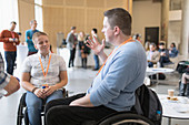 Business people in wheelchairs talking at conference