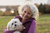 Portrait smiling, happy active senior woman holding dog