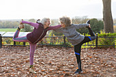 Active senior women friends stretching in autumn park