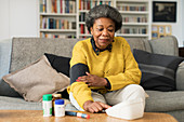 Senior woman checking blood pressure in living room