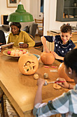 Family carving Halloween pumpkins at dining table