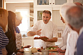 Senior friends listening to chef in pizza cooking class