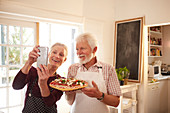 senior couple taking selfie with pizza at cooking class