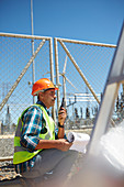 Engineer with walkie-talkie at sunny power plant
