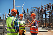 Engineers with digital tablet at sunny power plant