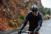 Dedicated young man cycling on rainy road