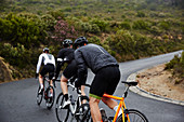 Male cyclists cycling uphill on road