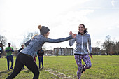 Women high-fiving, exercising in park