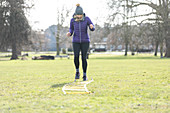 Woman doing speed ladder drill in sunny park