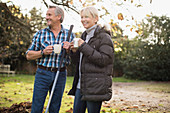 Mature couple raking autumn leaves