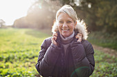 Portrait mature woman in parka in sunny park