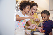 Playful mother and children baking in kitchen