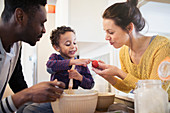 Parents and curious toddler son baking in kitchen