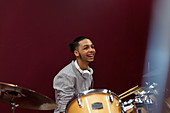 Happy teenage boy musician playing drums