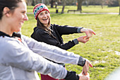 Female runners stretching wrists in park