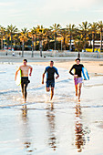 Enthusiastic male surfers running in surf