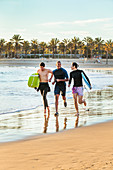 Enthusiastic male surfers running with surfboards