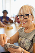 Portrait happy senior woman playing cards