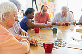 Senior woman assembling jigsaw puzzle with friends