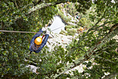 Woman zip lining among trees in woods