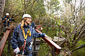 Smiling woman preparing to zip line in woods