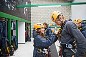 Woman helping man with zip line equipment