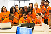 Happy hackers sharing laptop, coding at hackathon
