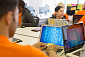 Hackers at laptops coding for charity at hackathon