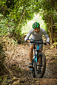 Happy man mountain biking on trail in woods