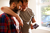 Male gay couple looking at ultrasound photo