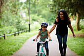 Happy mother teaching daughter how to ride bike