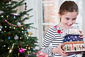 Smiling, eager girl gathering Christmas gifts