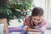 Smiling, curious girl opening Christmas gift