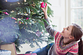 Curious girl touching ornament on Christmas tree