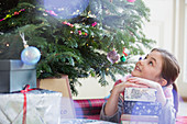 Curious girl with stack of gifts looking up tree