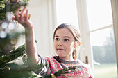 Curious girl touching ornament on Christmas tree