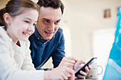 Father with smart phone using laptop with daughter
