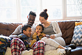 Young family relaxing in pyjamas on sofa