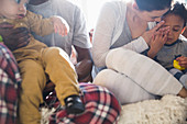 Young family in pyjamas relaxing on sofa