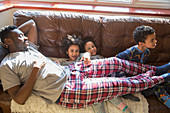Kids in pyjamas cuddling with father on sofa