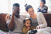 Laughing, happy multi-ethnic family on sofa