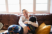 Happy, carefree mother cuddling with son on sofa