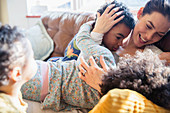 Affectionate mother and children cuddling on sofa