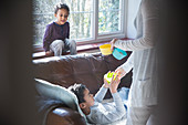 Mother giving snacks to children in living room