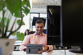 Smiling businessman using digital tablet in office
