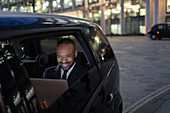 Businessman using laptop in crowdsourced taxi