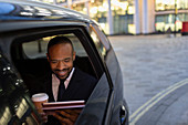 Businessman using tablet in crowdsourced taxi